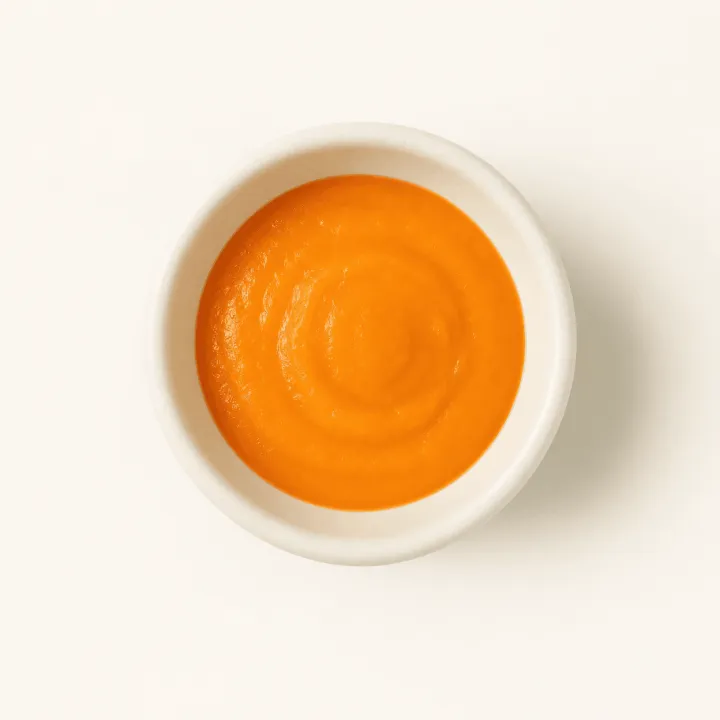 A small bowl of smoothly puréed carrot, photographed from above.