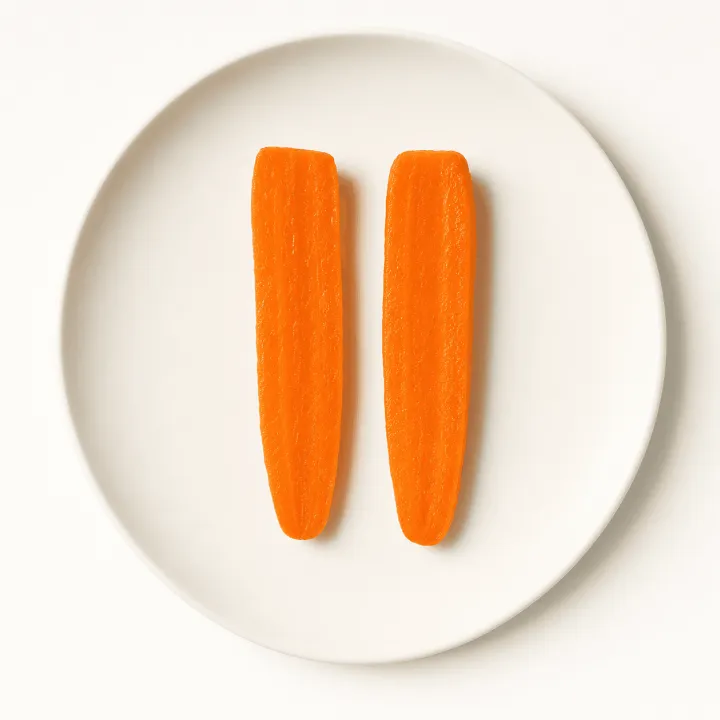 Two soft-cooked carrot sticks on a white plate, photographed from above.